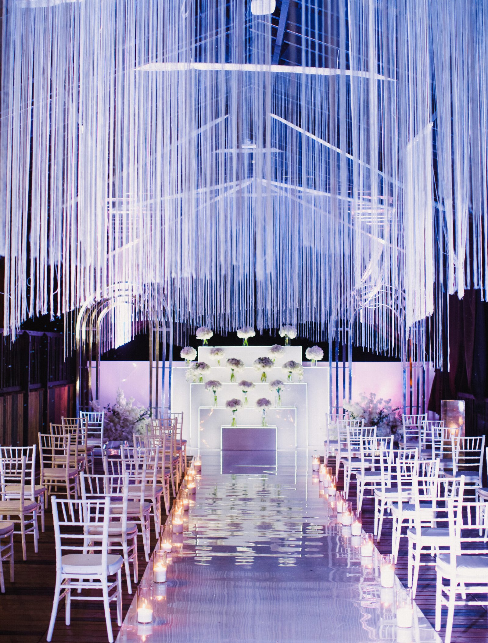 white chairs in wedding hall and wedding ceremony venue in white and violet and festoon shining